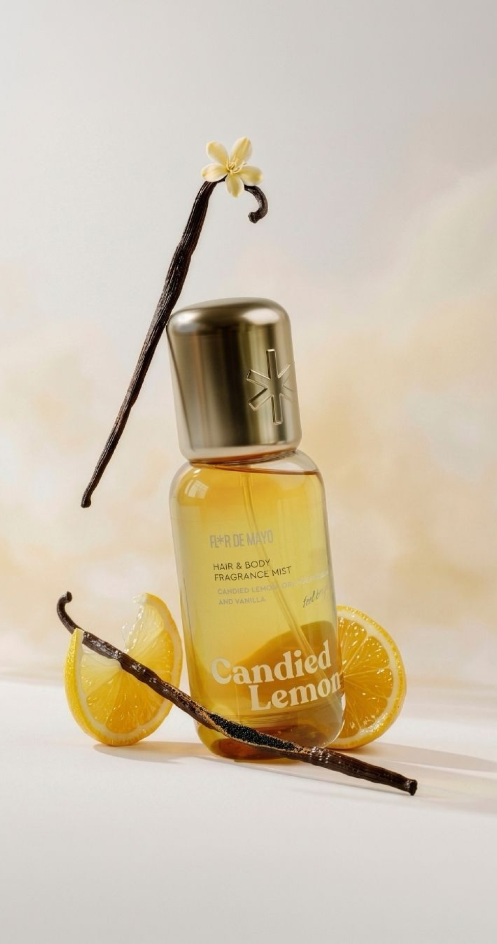 Perfume bottle labeled "Candied Lemon," surrounded by vanilla pods and lemon slices, set against a soft background.